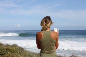 Woman overlooking ocean with a cup of coffee